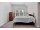 Cozy bedroom featuring a dark wood poster bed, a window view, and soft, neutral carpet at 244 Sturry Dr, Mcdonough, GA 30252