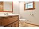 Bathroom featuring wooden vanity with steel sink, toilet, and a window at 215 Kingswood Dr, Fayetteville, GA 30215