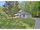 View of a two-story home with an attached garage surrounded by mature trees and lawn at 215 Kingswood Dr, Fayetteville, GA 30215