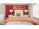 Bedroom with white bed frame, red accent wall, and orange bedding at 113 Broder Farms Dr # 387, Stockbridge, GA 30281