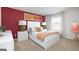 Bedroom with white bed frame, red accent wall, and orange bedding at 113 Broder Farms Dr # 387, Stockbridge, GA 30281