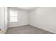 A carpeted room with neutral walls, window, and a white door offers a blank canvas at 205 Friendship Oak Way, Hampton, GA 30228