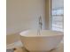 Freestanding tub in a bathroom with tile floors and a window with a view to the outdoors at 3505 Gum Creek Rd, Oxford, GA 30054