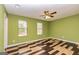 Well-lit bedroom featuring two windows, ceiling fan and wood-look floors at 2994 Meadow Wood Ct, Lawrenceville, GA 30044