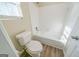 Well-lit bathroom with a white toilet, bathtub, and window with blinds, complemented by modern wood-style flooring at 1129 Winston Dr, Decatur, GA 30032