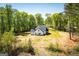 Aerial view of a charming single-Gathering home nestled among lush trees, with white siding, a black roof, and a spacious lawn at 90 Ayers Rd, Bowdon, GA 30108