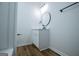 Bathroom featuring wood-look floors, white vanity with round mirror, and a shower behind it at 90 Ayers Rd, Bowdon, GA 30108