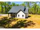 Charming single-Gathering home with white siding, black roof, and covered patio surrounded by trees and an expansive green lawn at 90 Ayers Rd, Bowdon, GA 30108