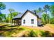 Charming single-Gathering home with white siding, black roof, and covered patio surrounded by trees and an expansive green lawn at 90 Ayers Rd, Bowdon, GA 30108