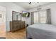 Neutral bedroom features wood-look floors, a ceiling fan, a dresser with mirror, and windows with decorative curtains at 1302 Ladd St, Atlanta, GA 30310