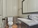 Neutral powder room features elegant wainscoting, dark cabinets, granite countertop, and decorative mirror at 230 Hedgewick Way, Tyrone, GA 30290