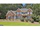 Stately brick home with blue shutters and a manicured lawn with mature landscaping and a welcoming porch at 230 Hedgewick Way, Tyrone, GA 30290