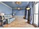 A spacious formal living room featuring blue walls, decorative wainscoting, hardwood floors and modern lighting at 230 Hedgewick Way, Tyrone, GA 30290