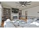 Cozy living room with a fireplace, built-in bookshelves, hardwood flooring, and a stylish ceiling fan at 230 Hedgewick Way, Tyrone, GA 30290