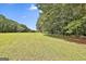 View of mature trees surrounding a large, grassy field on the property at 230 Hedgewick Way, Tyrone, GA 30290