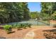 A view of a community tennis court surrounded by a high black chain link fence and dense trees at 230 Hedgewick Way, Tyrone, GA 30290