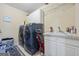 Practical laundry room with sink, washer, dryer, shelving and tile floor at 25 Abelia Dr, Covington, GA 30014