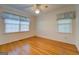 Bright bedroom with hardwood floors, ceiling fan, and two windows with window treatments at 155 Island Shoals Rd, Covington, GA 30016