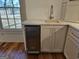Wet bar with wine refrigerator, custom cabinets and countertop next to a window at 213 W Hightower Trl, Social Circle, GA 30025