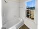 Clean, well-lit bathroom featuring a bathtub with shower and a window, offering a peaceful view at 3905 Colonial Sw Trl, Lilburn, GA 30047