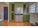 Stainless steel refrigerator flanked by green cabinets in a kitchen at 5117 Indie Se Cir, Covington, GA 30014