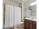 Well-lit bathroom featuring a vanity with dark wood cabinets and a shower with neutral-toned tiling at 301 Dunstans Pass, Marietta, GA 30066