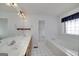 Bright bathroom with double sink vanity, tiled floors, a large mirror, and a soaking tub next to a window at 253 Edenwylde Ct, Hampton, GA 30228