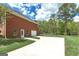 Side view of brick home with three car garage and long driveway with lush yard and blue skies at 253 Edenwylde Ct, Hampton, GA 30228