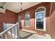 Inviting front porch with brick facade and arched windows offering a glimpse of the entry at 253 Edenwylde Ct, Hampton, GA 30228