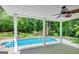 View of the sparkling blue in-ground pool and backyard from the covered back porch with ceiling fan at 90 Barrington Grange Dr, Sharpsburg, GA 30277