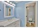 Blue bathroom featuring a sink with drawers, a mirror, lighting, and view of a toilet in an adjacent space at 90 Barrington Grange Dr, Sharpsburg, GA 30277