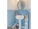 Powder room with pedestal sink, oval mirror, and blue accent wall at 4937 Lower Elm St, South Fulton, GA 30349