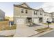 Two-story townhome with gray siding, white garage doors, and a small front yard at 4937 Lower Elm St, South Fulton, GA 30349