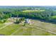 Aerial view showcasing a green home with outbuildings, surrounded by fenced pastures and mature trees at 3170 Double Bridges Rd, Rutledge, GA 30663