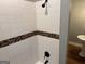 White tiled shower with black fixtures and a horizontal band of multi-colored decorative tiling at 1771 Ware Ave, East Point, GA 30344
