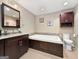 A bathroom with dark wood cabinets, granite counters, a large soaking tub, and a toilet at 107 Stratford Ct, Peachtree City, GA 30269