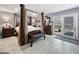 A main bedroom featuring a wooden four-poster bed, light-colored hardwood floors, and sliding glass door leading to outdoor scenery at 107 Stratford Ct, Peachtree City, GA 30269