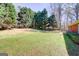 A beautifully lawned backyard with mature trees offers a serene view from this home at 25 Brookstone Ct, Covington, GA 30016
