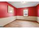 Bedroom with red walls, light beige trim, and hardwood flooring at 5427 Forest Pines Dr, Lithonia, GA 30058