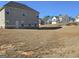 A view of a spacious backyard with dormant grass and several craftsman style homes in the distance at 1455 Weeping Tree Cir, Auburn, GA 30011