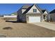 Exterior home view with a spacious yard, two-car garage, and neutral siding at 1455 Weeping Tree Cir, Auburn, GA 30011