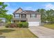 Charming two-story home featuring a manicured lawn, flower beds, and an attached two-car garage at 8264 Milam Loop, Fairburn, GA 30213