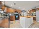 A well-lit kitchen featuring wood cabinets, black appliances, and a white kitchen island at 8264 Milam Loop, Fairburn, GA 30213