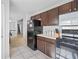 View of kitchen with black refrigerator, dark brown cabinets, and tile floor at 119 Bombay Ln, Grantville, GA 30220