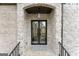 Elegant stone arched entryway with modern black framed glass double doors and lantern lighting at 220 Early Parkway Se Dr, Smyrna, GA 30082
