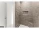 Modern tiled shower with a built-in seat, sleek showerhead, a niche, and glass door at 220 Early Parkway Se Dr, Smyrna, GA 30082