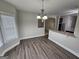 Dining area with dark wood floors, modern chandelier, open access to kitchen, and bright bay window at 7214 Bedrock Cir, Lithonia, GA 30038