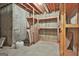 Unfinished basement with concrete floor, exposed ceiling and wood shelving for storage at 337 Legacy Ln, Peachtree City, GA 30269