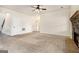 Spacious living room with a stone fireplace, a ceiling fan, neutral carpet, and access to other rooms at 1205 Heartwood Ave, Mcdonough, GA 30253