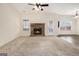 Bright living room with a stone fireplace, neutral carpet, a ceiling fan, and multiple windows at 1205 Heartwood Ave, Mcdonough, GA 30253